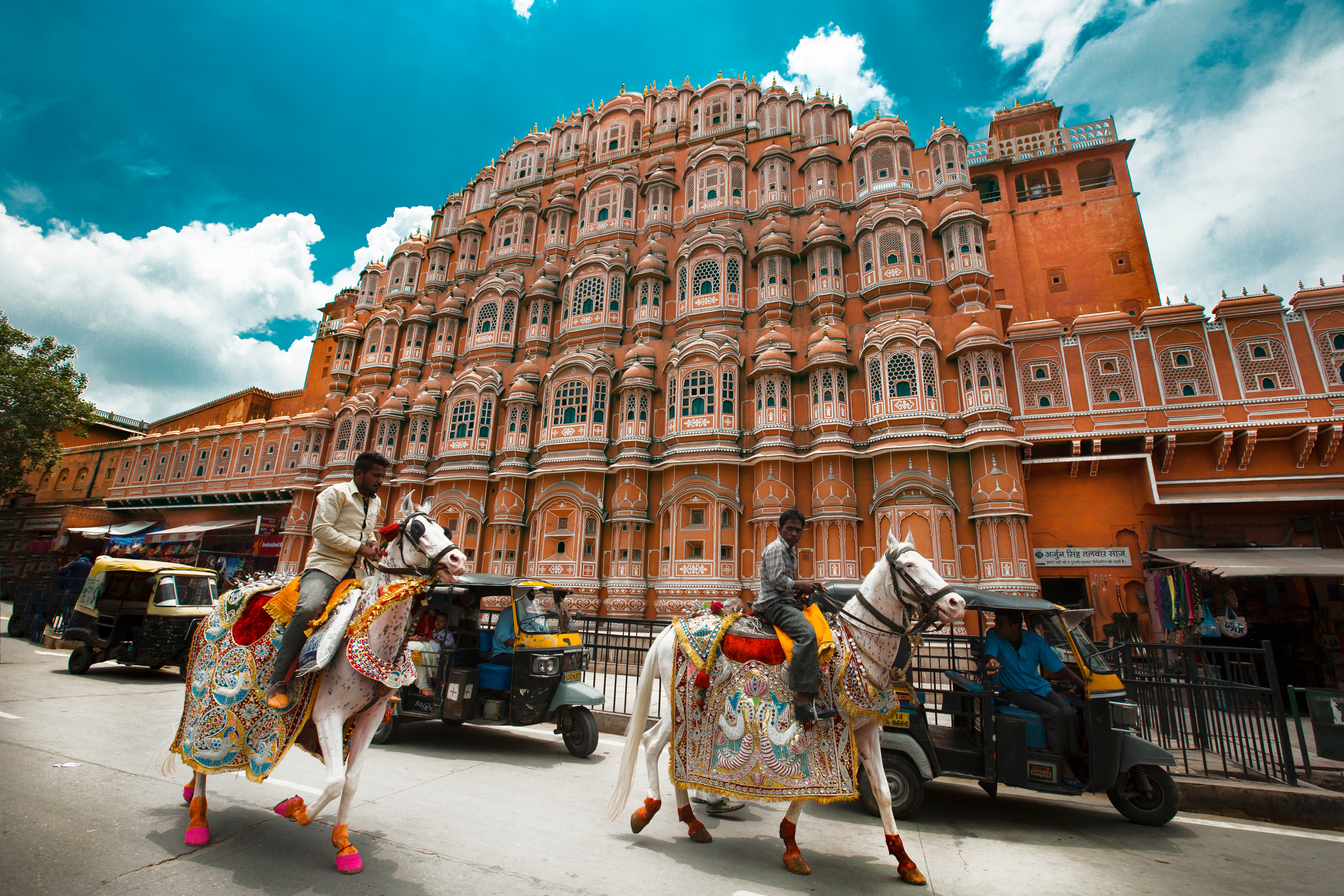 Hawa Mahal is a wonder of Jaipur. It's a beautiful palace. Here is the honeycomb structure of Hawa Mahal with people on horses on the road. 